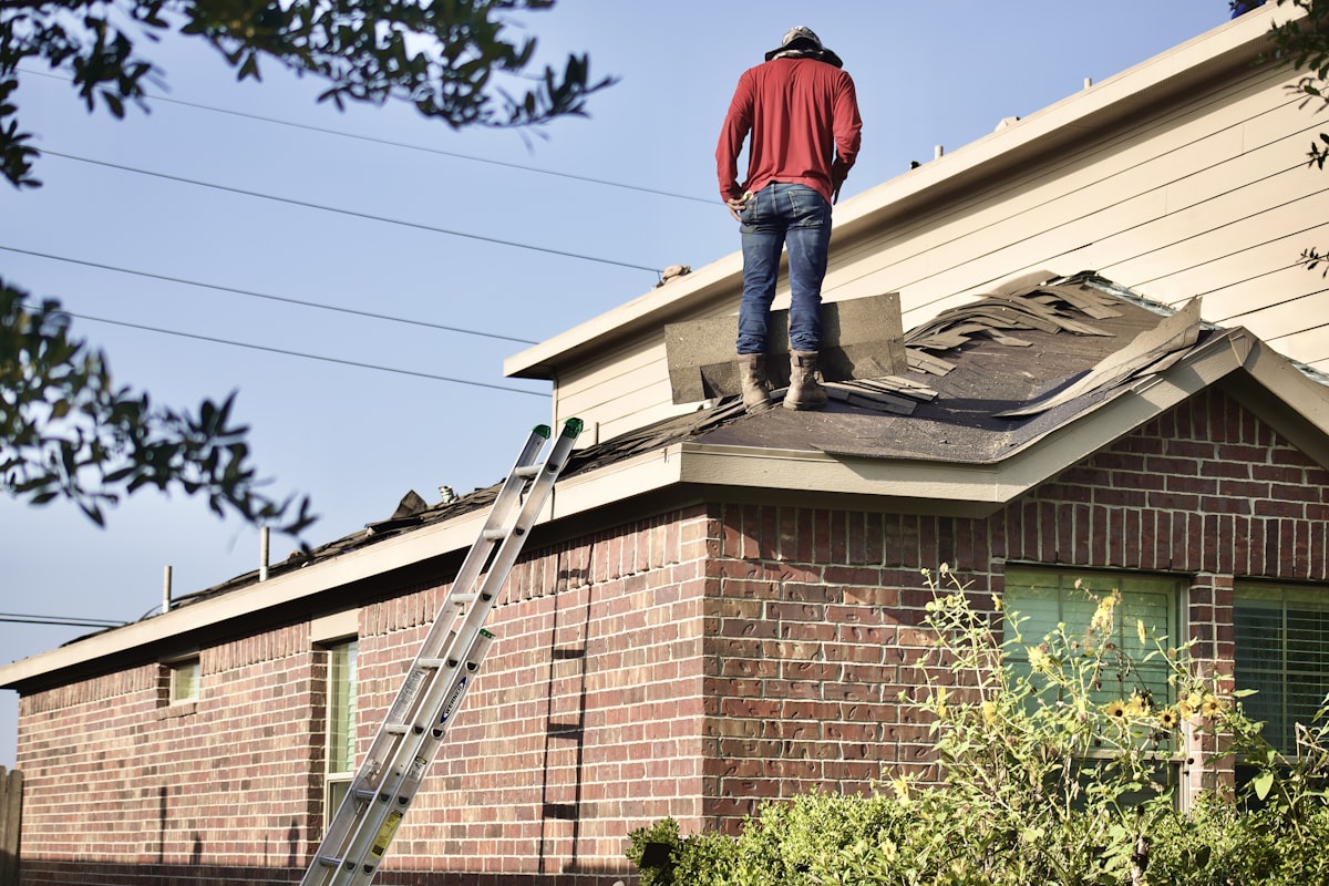 Roofer inspecting storm damage on Dallas home